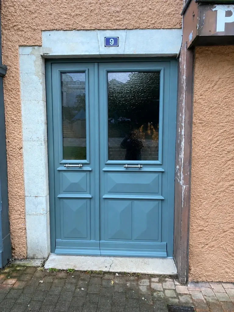 Porte d’entrée bois à deux vantaux bleu gris, vitrée en partie haute, avec panneaux en pointes de diamant (Menuiserie Feugas)