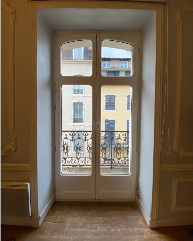 Porte-fenêtre bois blanche à deux vantaux cintrés donnant sur un balcon en fer forgé (Menuiserie Feugas)