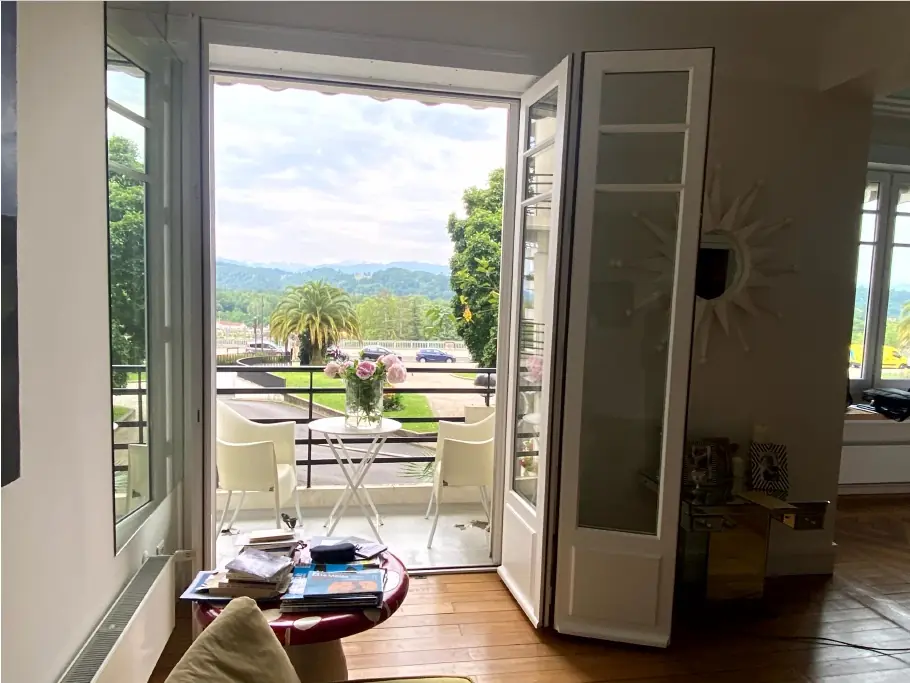 Porte-fenêtre bois blanche ouverte sur un balcon avec vue sur les montagnes (Menuiserie Feugas)